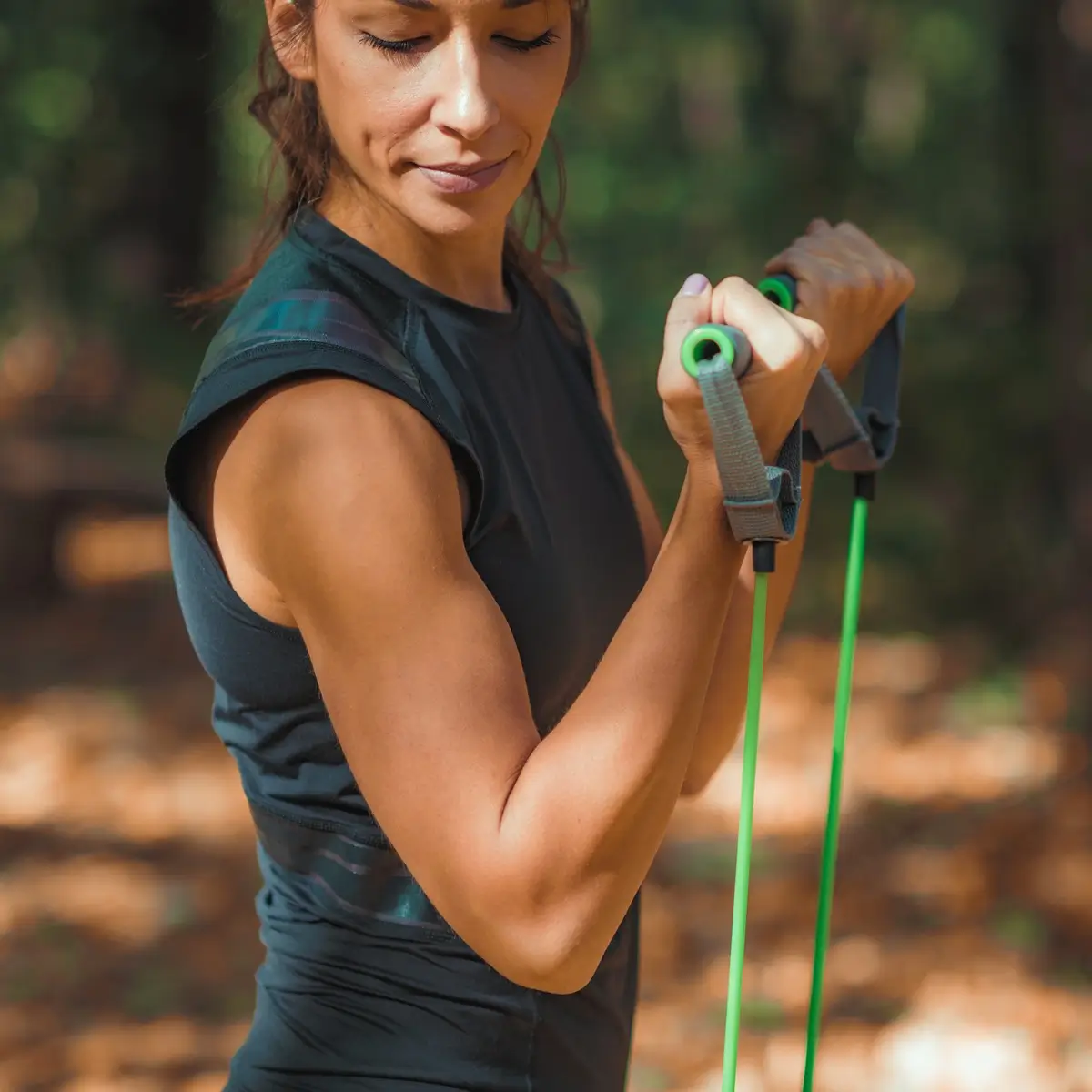 Fitt nő erősít az edző gumikötéllel egy parkban