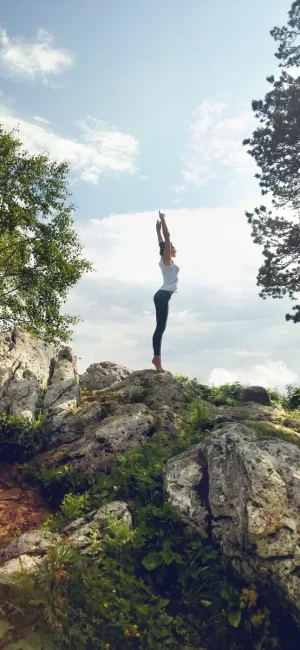 Egy karcsú nő jógázik a hegyen
